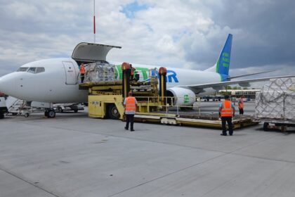 Two people helping loading the cargo inside a SolitAir aircraft.