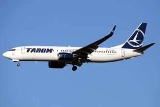 A TAROM Boeing 737-800 aircraft flying through the blue sky.