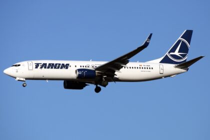 A TAROM Boeing 737-800 aircraft flying through the blue sky.