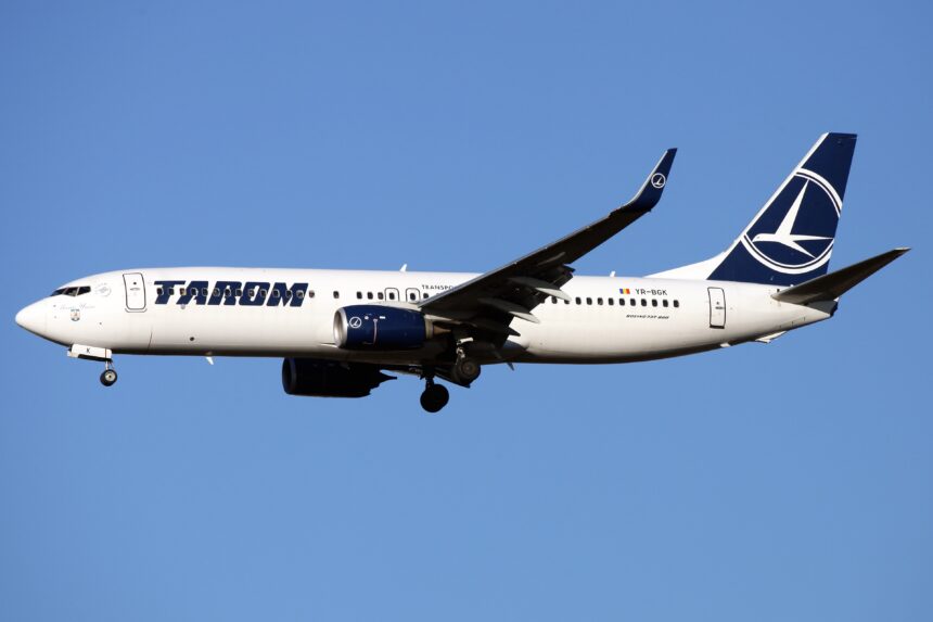 A TAROM Boeing 737-800 aircraft flying through the blue sky.