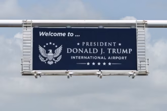 A navy road sign picture on the way into Palm Beach County's Airport, reading "Welcome to... President Donald J. Trump International Airport."