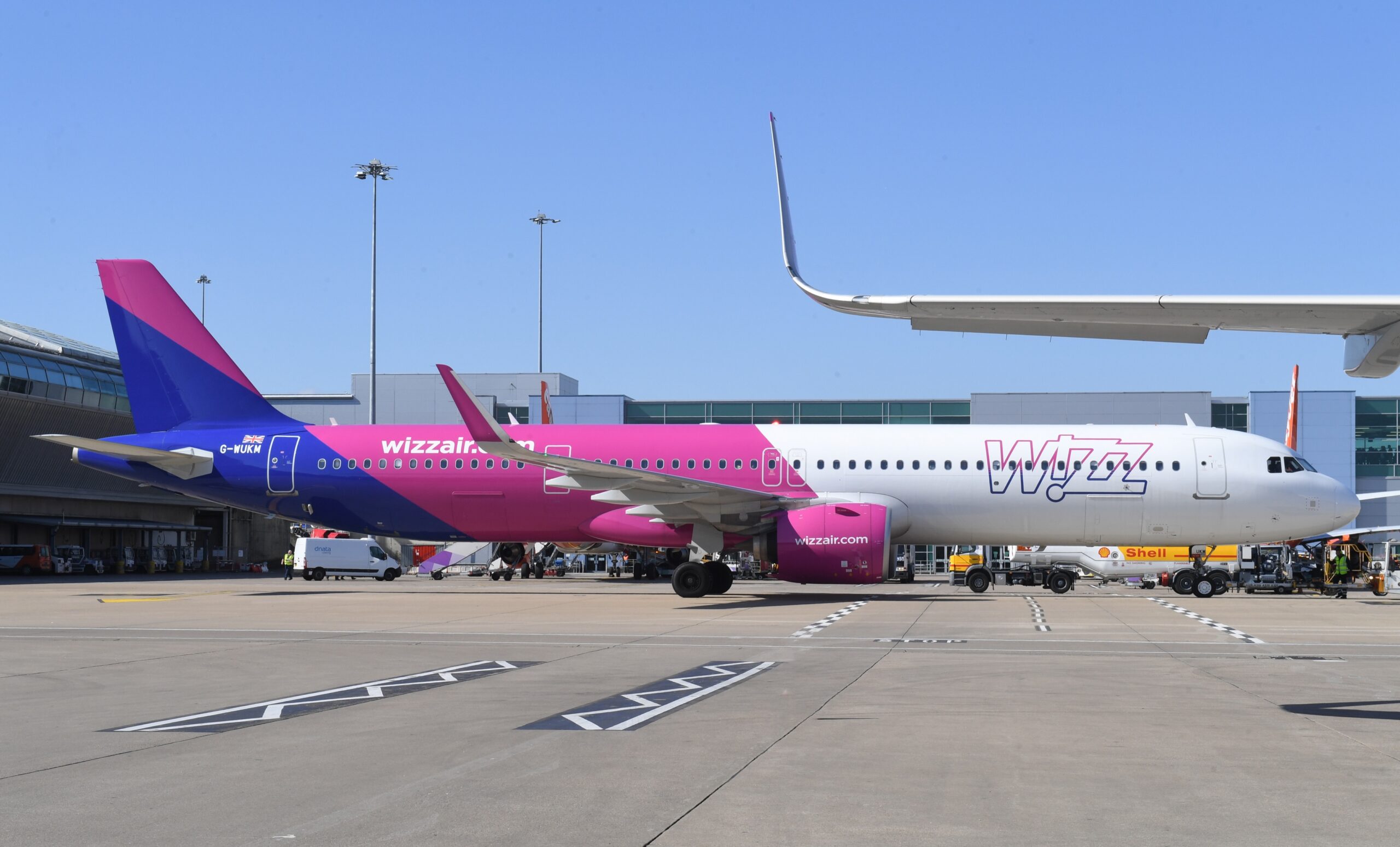 A purple, white, and blue, Wizz Air flight stationed