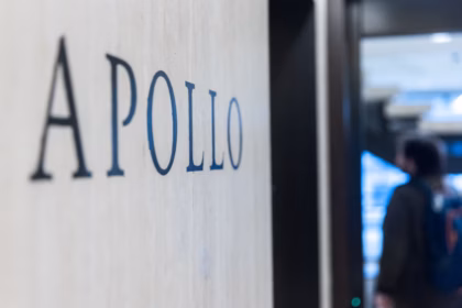 The Apollo Global Management logo engraved into a grey wall, with a figure blurred in the background.