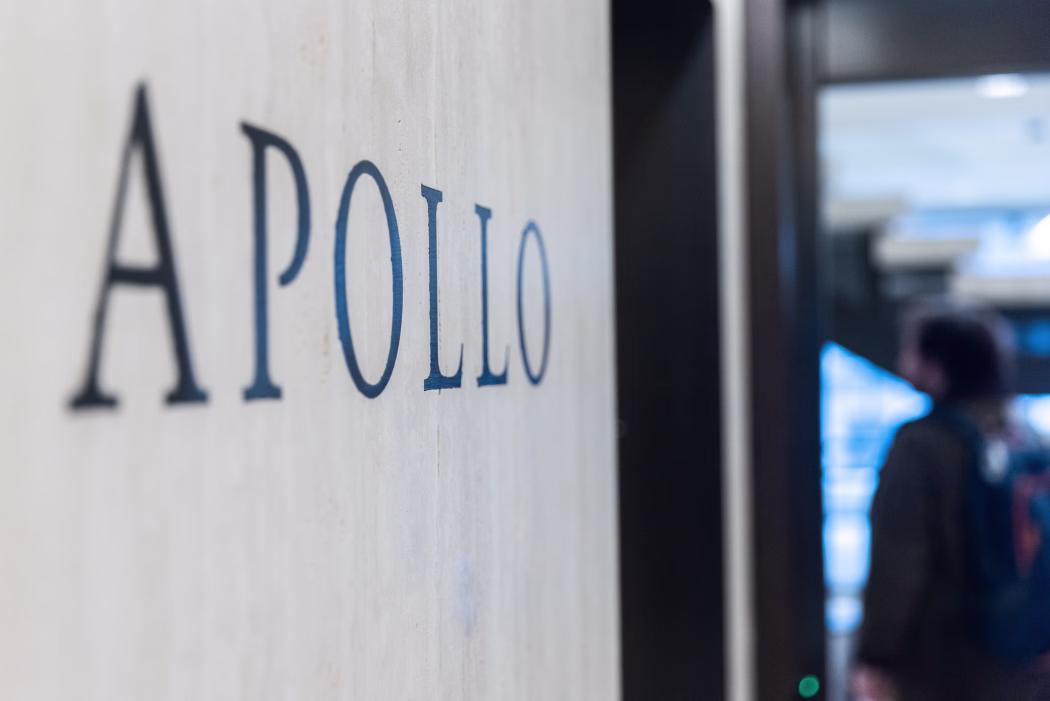 A sign displaying 'Apollo' on a wall, taken from an angle and showing a blurred figure in the background.