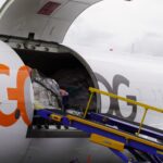 Close-up view of open cargo compartment door on a GOL airplane. Inside the hold, large pallets of wrapped cargo and boxes are visible.