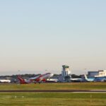 An image of Bristol Airport tarmac surrounded by green grass with various EasyJet planes seen on the runway and a clear bright blue sky backdrop.