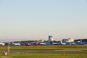 An image of Bristol Airport tarmac surrounded by green grass with various EasyJet planes seen on the runway and a clear bright blue sky backdrop.