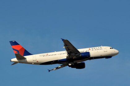 A delta Airbus with a blue tail flying midair with a clear blue sky background.