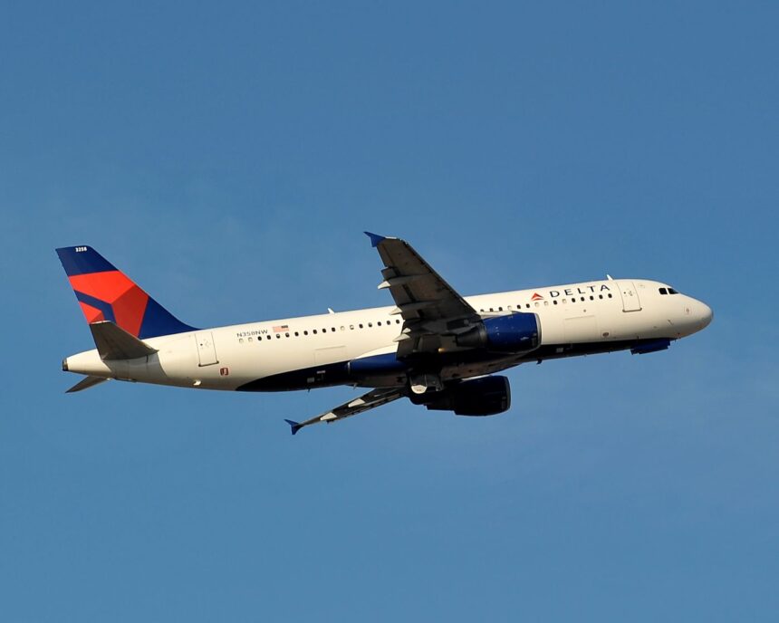 A delta Airbus with a blue tail flying midair with a clear blue sky background.