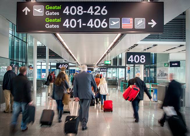 Passengers rushing through a busy Dublin Aiport, headed towards gates. 