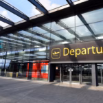 The Departures gate at Gatwick airport, showing the 'Departures' sign in yellow letters.