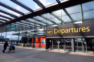 The Departures gate at Gatwick airport, showing the 'Departures' sign in yellow letters.