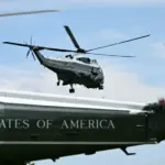 Tail of a Trump's Marine One and another helicopter flying behind it.