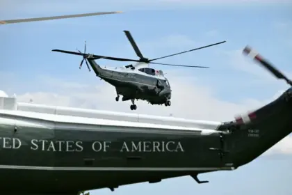Tail of a Trump's Marine One and another helicopter flying behind it.