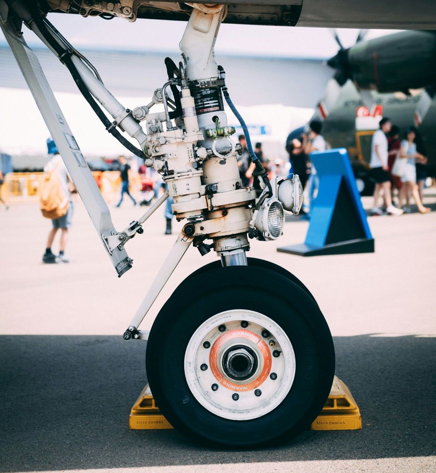Nose landing tyre propped up to be fixed with people walking in the background