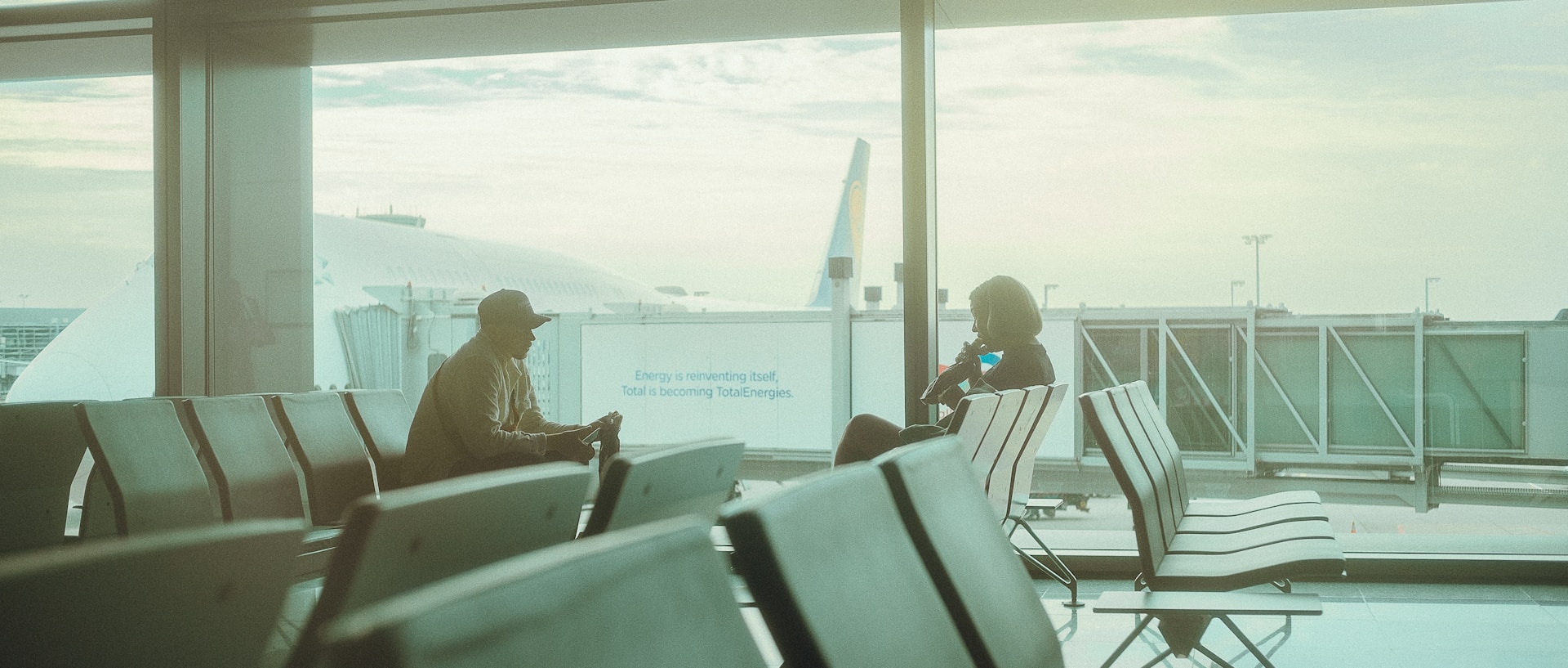 Empty airport with two people sitting with airplane in the background