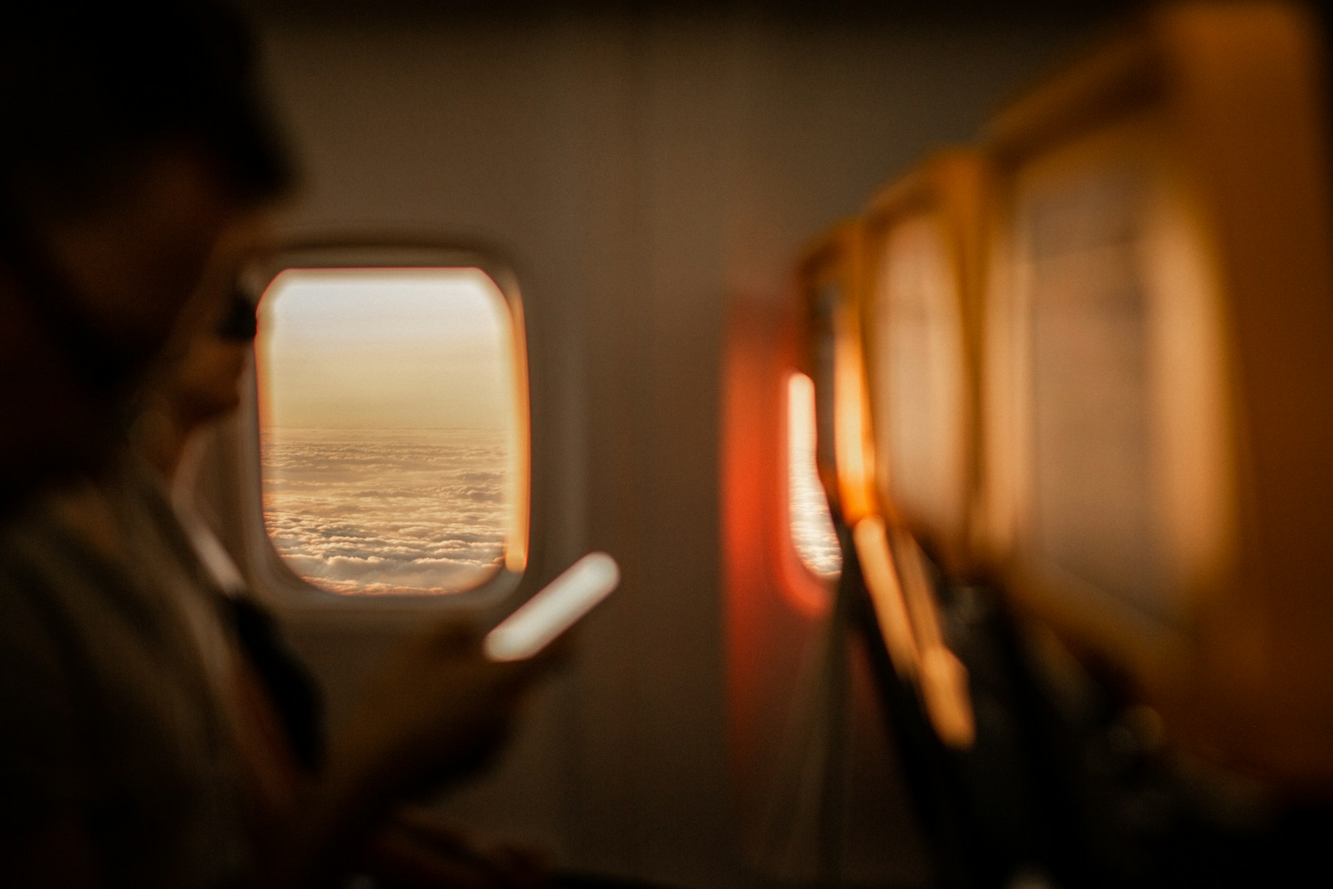 woman using phone in airplane with warm lighting