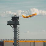 A DHL Aviation jet with its iconic bright yellow body and red font, setting off from Leipzig/Halle Airport (LEJ).