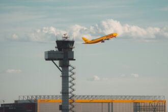 A DHL Aviation jet with its iconic bright yellow body and red font, setting off from Leipzig/Halle Airport (LEJ).
