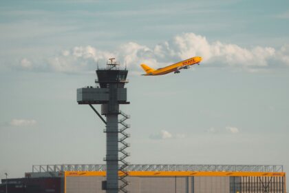 A DHL Aviation jet with its iconic bright yellow body and red font, setting off from Leipzig/Halle Airport (LEJ).