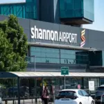 A woman with a suitcase and backpack walking through an airport car park