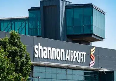 A woman with a suitcase and backpack walking through an airport car park