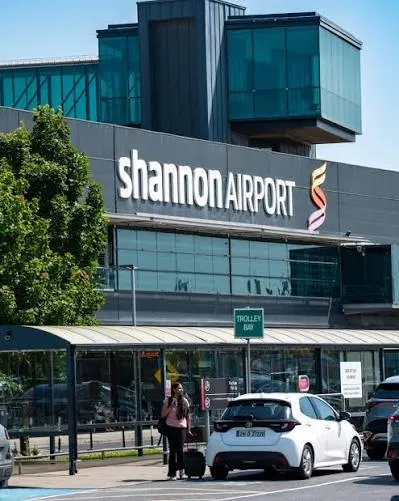 A woman with a suitcase and backpack walking through an airport car park