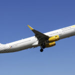 Vueling A321 mid-flight with a blue sky as the background.