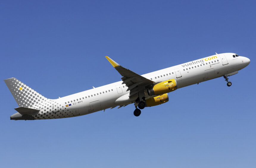 Vueling A321 mid-flight with a blue sky as the background.