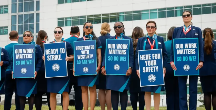 A row of WestJet flight attendants standing on a picket line with signs reading 'Our work matters, so do we!', 'Ready to strike.', and 'Frustrated with WestJet? So are we.'