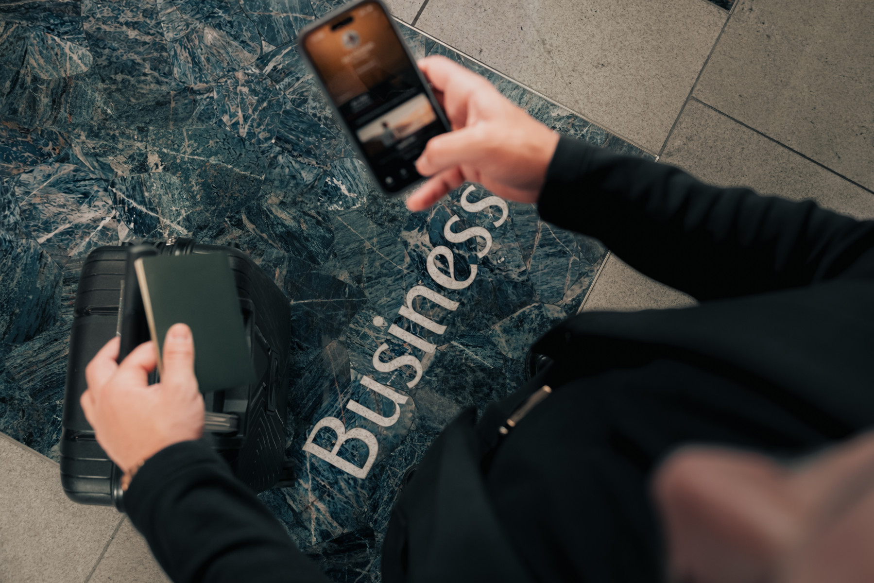 Photograph depicting an Emirates customer holding their smartphone and trying to access Emirates Skywards app while standing near the Business Class entrance area.