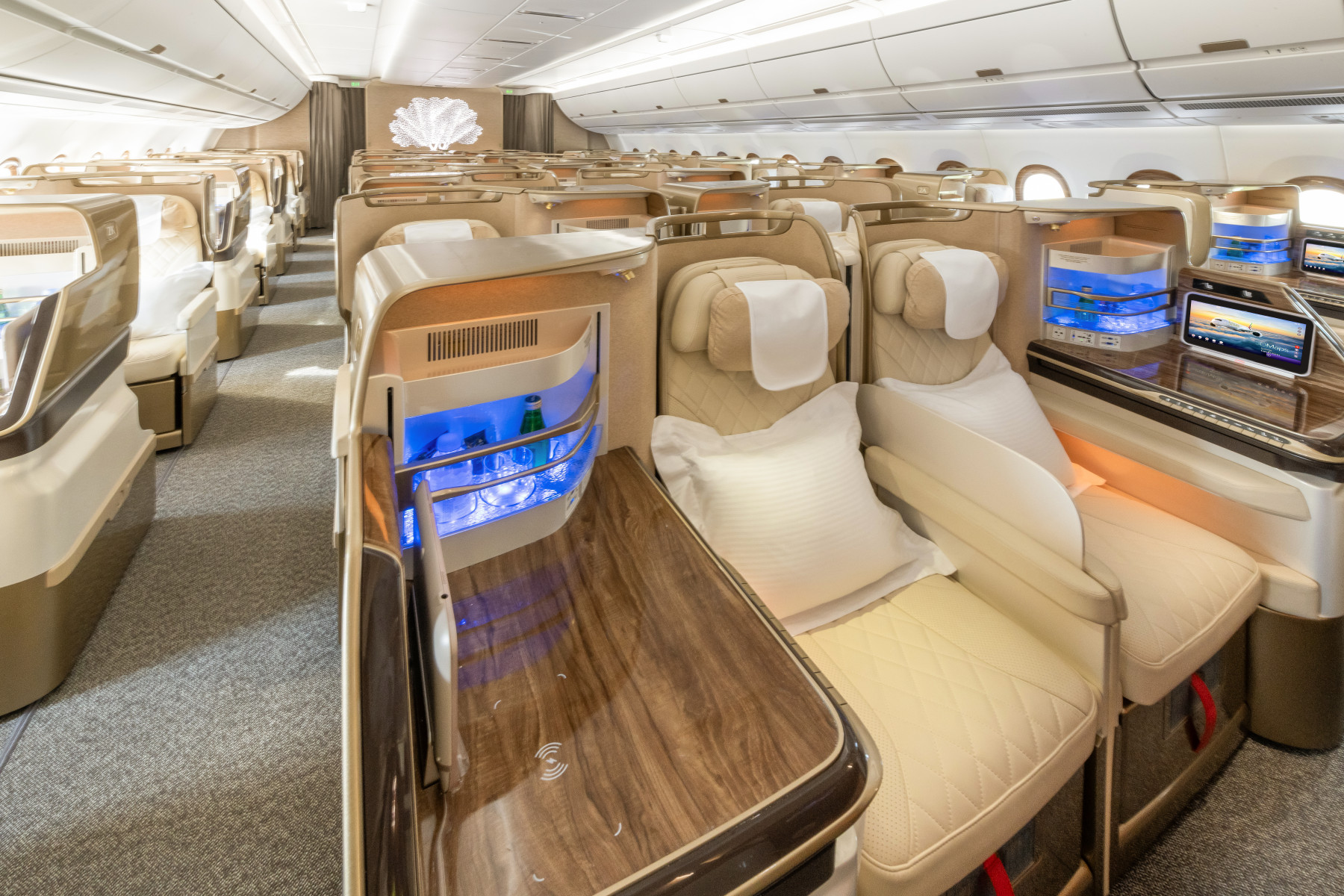 Photograph depicting the interior of the Business Class cabin onboard the Emirates A350 including the leather seats and attached minibar. 
