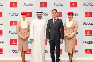 Four people stand next to each other in front of a promotional screen