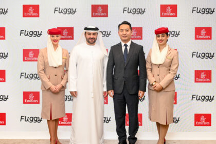 Four people stand next to each other in front of a promotional screen