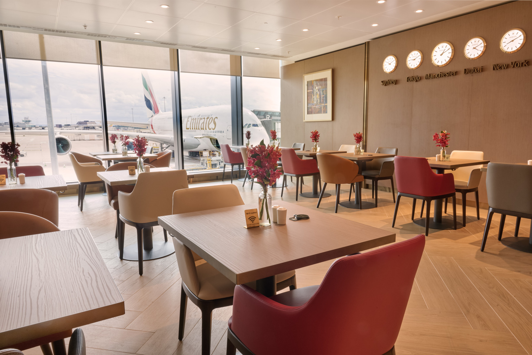Photograph depicting the stylish seating facilities at the new Emirates lounge at Manchester airport along with a view of the runway and the direct lounge-to-aircraft boarding.