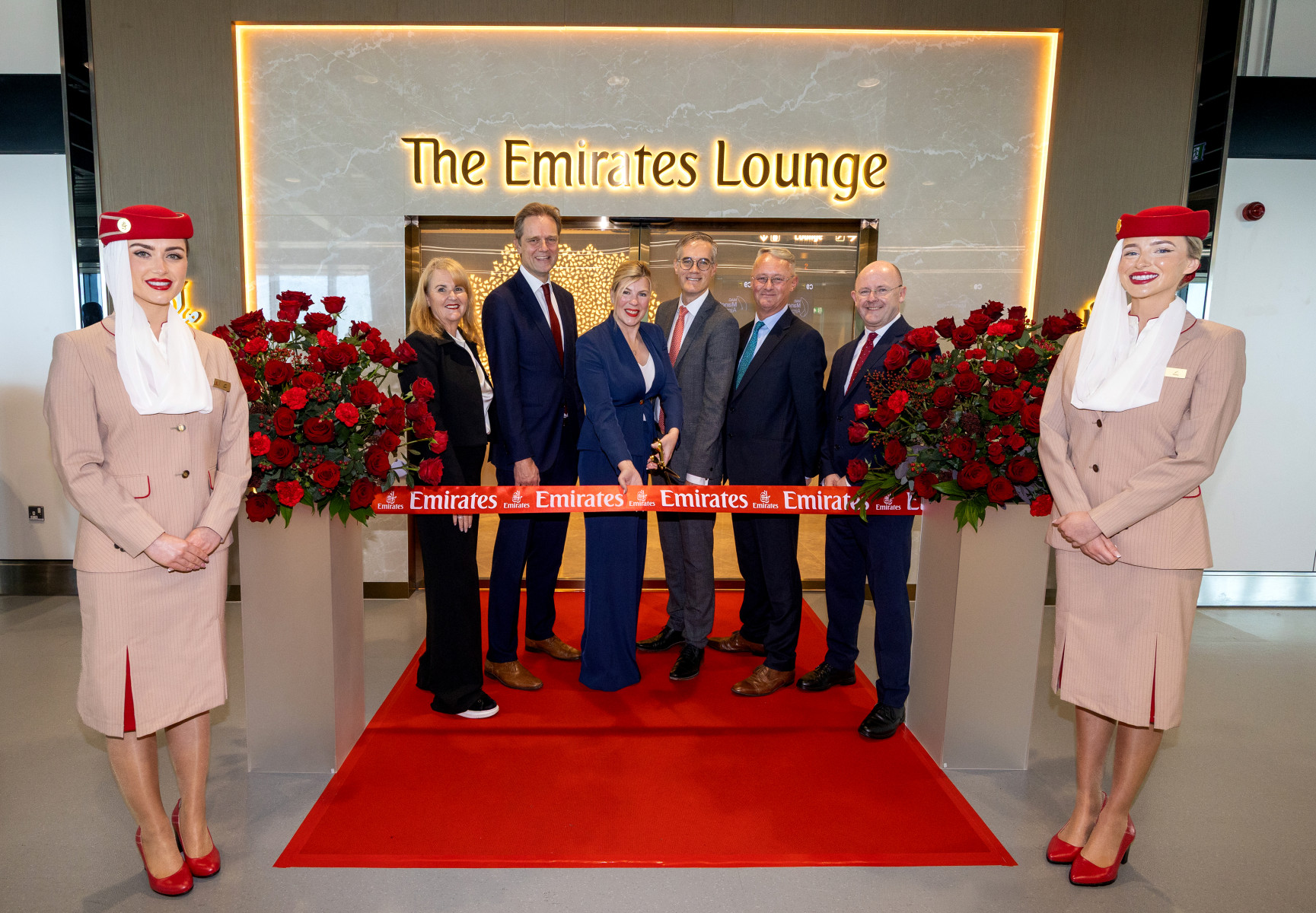 Photograph depicting Emirates air hostesses and staff members at the ribbon cutting ceremony to mark the opening of Emirates' new Manchester airport lounge.