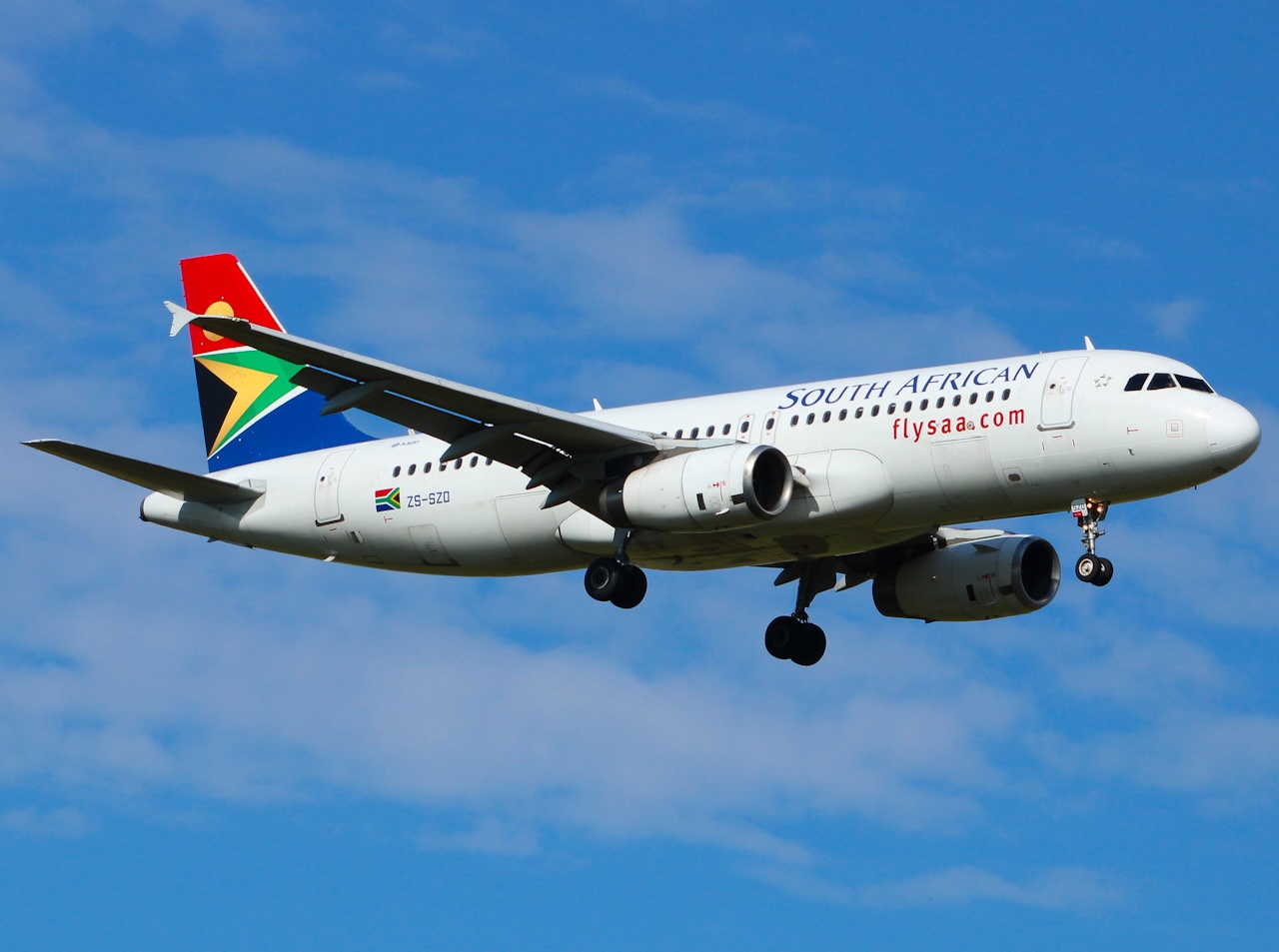 South African Airlines' Airbus A320-232 in the air with its landing gear extended and both engines visible.
