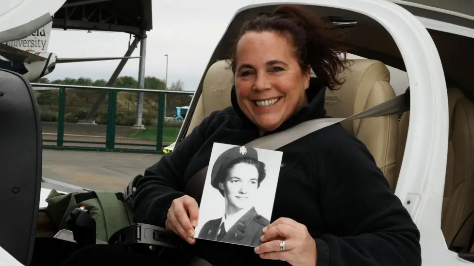 Jo Salter sitting inside an aircraft holding an old picture of herself when she was in the UK's Royal Air Force.