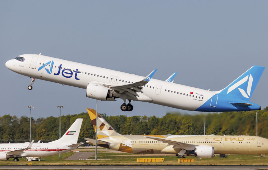 An A321neo aircraft taking off from the runway. An Etihad aircraft can be seen on the runway below the A321neo.