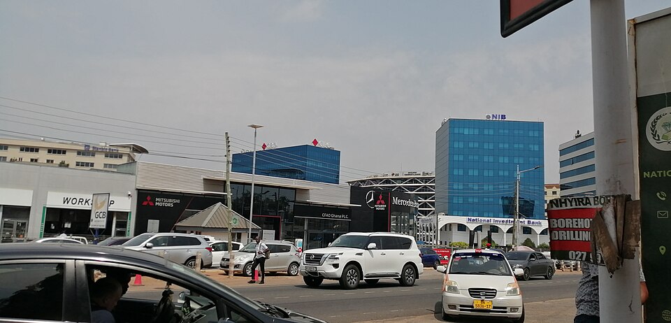 Image of kotoka international Airport near terminal 3 arrival opposite Africa World Airline in Ghana with a building on the right hand side, and half a dozen cars.