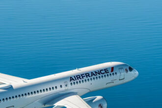 Photograph depicting the exterior of and Air France aircraft cruising at altitude above the ocean.