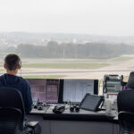 Image shows an air traffic controller looking out over runways.