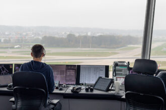 Image shows an air traffic controller looking out over runways.
