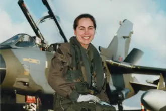 Jo Salter crouching in front of an aircraft wearing gear.
