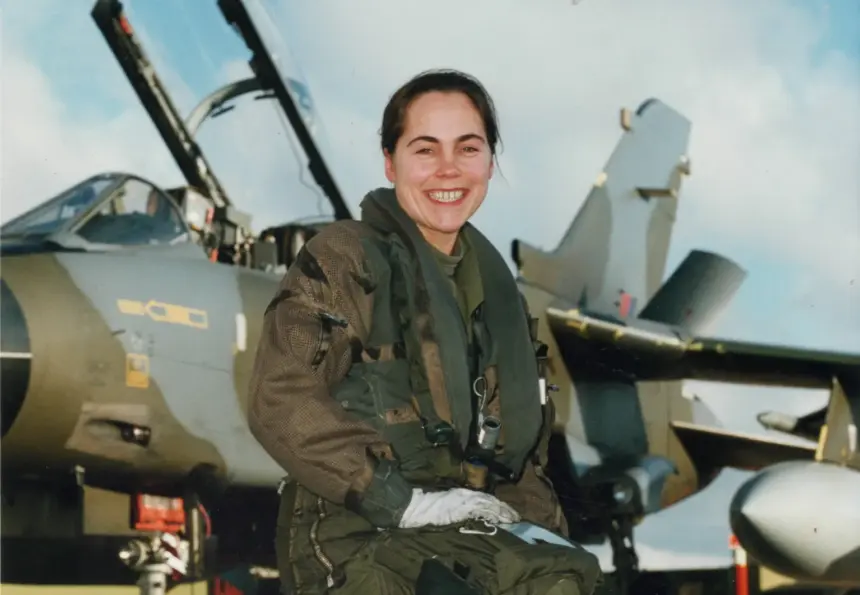 Jo Salter crouching in front of an aircraft wearing gear.