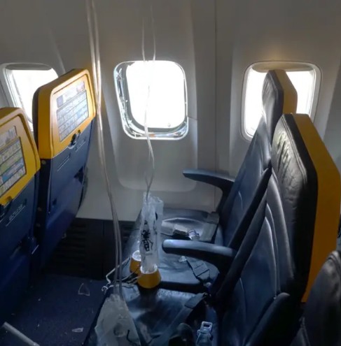 Picture shows the broken window on a Ryanair plane with oxygen masks hanging from the ceiling