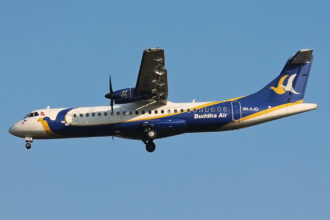 Buddha Air ATR 72 turboprop aircraft in flight with landing gear extended against a clear blue sky.