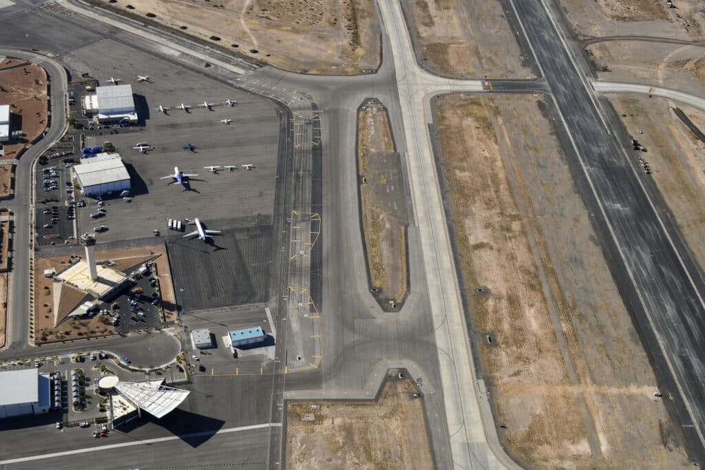 Aerial view of El Paso International Airport showing taxiways, runways, a control tower, and airplanes parked on the tarmac.