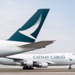 An image of two Cathay Cargo aircraft tail fin, with a Cathay Cargo Boeing 747 parked on the tarmac behind the tail wing aircraft