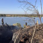 Emergency crews are pictured at the scene of the crash, overlooking the San Joaquin River on a sunny day.